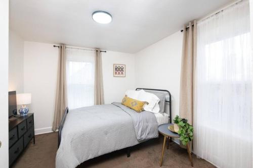 a white bedroom with a bed and a table at Cozy & Convenient Getaway 3BD 2BA Dog Friendly in Akron
