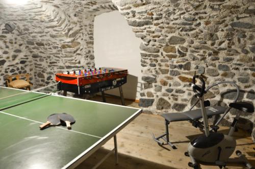a ping pong table in a room with a stone wall at Residence Ca' Delle Margherite in Pellizzano