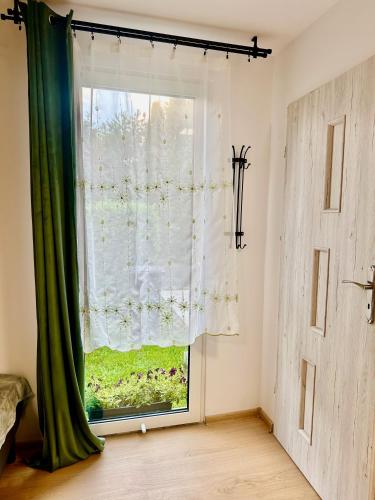 a window with a green curtain in a room at Apartament nr 1 lub 2 przy Sali Kominkowej in Przeczyce