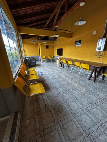 a waiting room with yellow chairs and a table at Casa do Loro Hospedagem in Curitiba