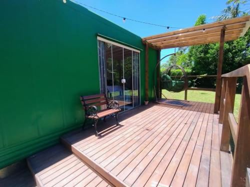 a green house with a bench on a wooden deck at Pousada e Restaurante Dona Siroba in Morretes
