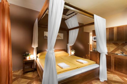 1 dormitorio con cama con dosel y cortinas blancas en Penzion V Roklich & Apartmens V Roklich en Ricany