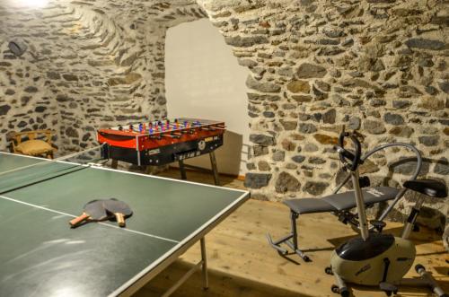 a ping pong table in a room with a stone wall at Residence Ca' Delle Margherite in Pellizzano