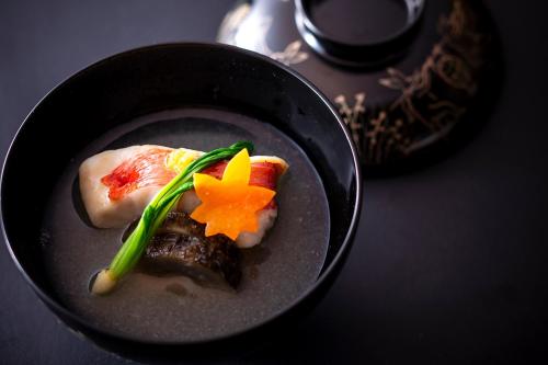 a black bowl of food with vegetables on a table at Hotel Utano Kyoto Besho in Kyoto