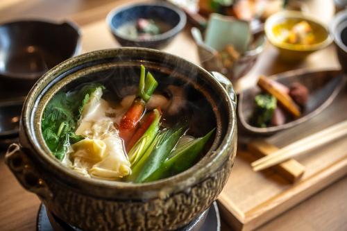 a bowl of soup with vegetables in it on a table at Hotel Utano Kyoto Besho in Kyoto