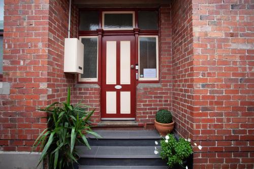 a red door on a brick building with plants at Ballarat Station Apartments Queen Studio With Spa in Ballarat