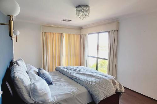 a bedroom with a bed with a large window at Tranquil Riverfront Oasis in Oatley
