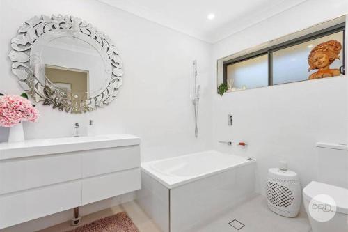 a white bathroom with a sink and a mirror at Tranquil Riverfront Oasis in Oatley