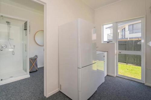 a kitchen with a white refrigerator and a window at Across the Road to the Beach - Beach House in Whitianga