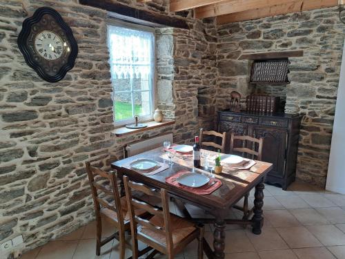 une salle à manger avec une table et une horloge au mur dans l'établissement Stone House near Penze River and Morlaix Bay, à Plouénan
