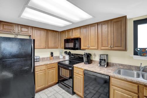 a kitchen with wooden cabinets and a black refrigerator at Wind Drift 501 by Vacation Homes Collection in Orange Beach