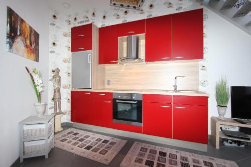 kuchnia z czerwonymi szafkami i zlewem w obiekcie Sandpiper w mieście Ypres