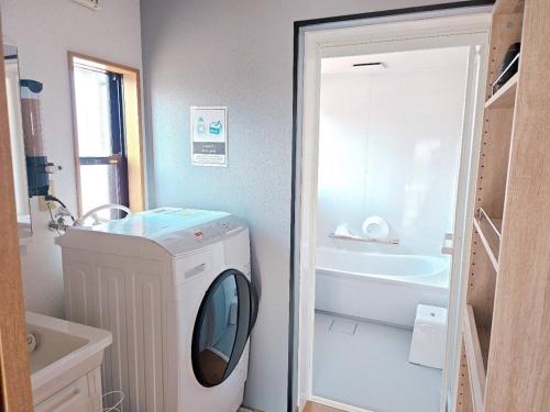 a bathroom with a washing machine and a bath tub at Shima City Detached house SKO1 in Katada