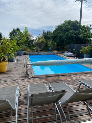 a swimming pool on a deck with chairs and a table at entre terre et mer in Sainte-Soulle
