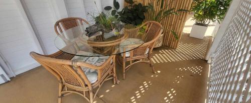 a glass table and four chairs with plants on it at Ribbonwood Bed & Breakfast, Emu Park Qld in Emu Park