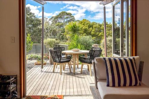a patio with a table and chairs on a deck at Welcome on Wilma by Waiheke Pure in Waiheke Island