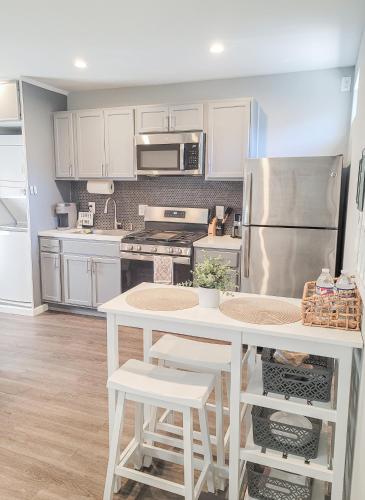 a kitchen with white cabinets and a white table with stools at Unique Studio in York in York