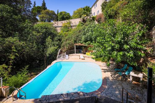 - une vue sur la piscine bordée d'arbres et un bâtiment dans l'établissement Le Vieux Moulin, Cotignac, à Cotignac
