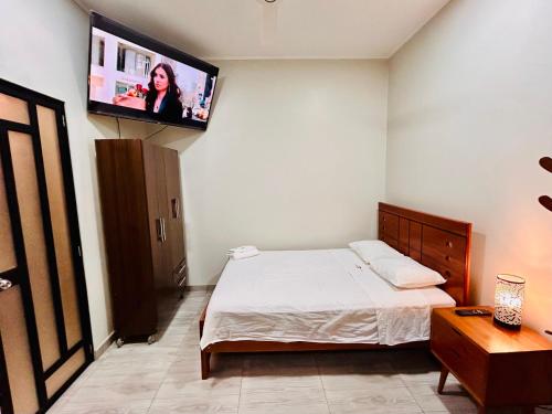 a bedroom with a bed and a tv on the wall at Habitación Céntrica en Iquitos - Casa Alemi 6 in Iquitos