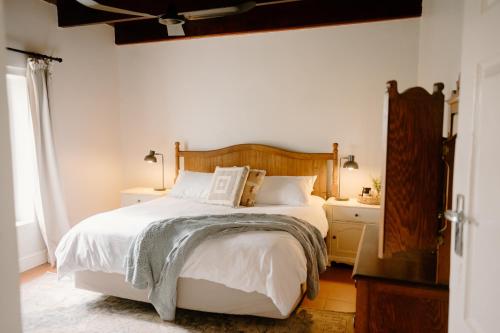 Un dormitorio con una gran cama blanca y una ventana. en Melkhout Farm Cottage, en Bonnievale