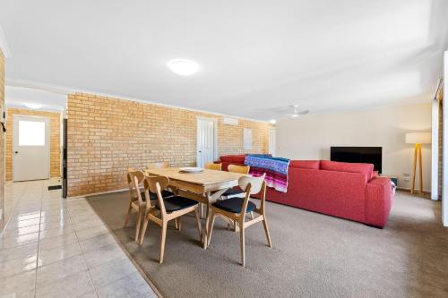 a living room with a table and a red couch at 7 - 9 Mort Ave Dalmeny in Dalmeny