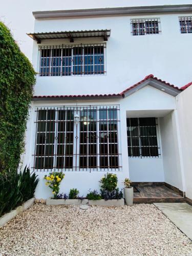 a white house with black windows at Casa G&V X9 personas in Santa Elena