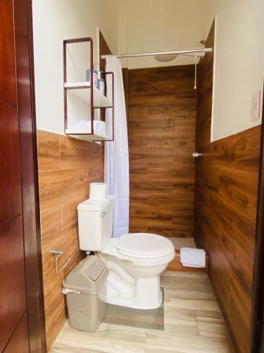a bathroom with a toilet and a wooden wall at Casa G&V X9 personas in Santa Elena