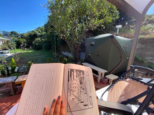 a person is reading a book on a table at Grace House グレイスハウス- Country Home Relaxation in Okawa