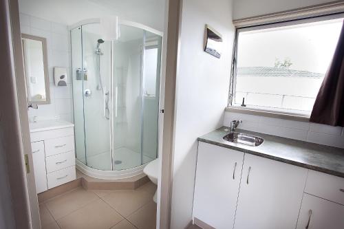 a bathroom with a shower and a sink at Blue Haven Motel in Mount Maunganui