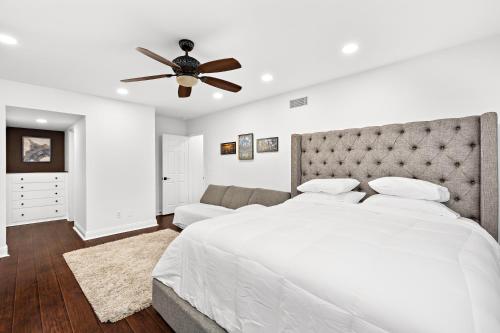a white bedroom with a bed and a ceiling fan at Villa Oasis: Unrivaled Views & Endless Space in Los Angeles