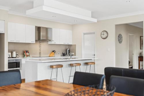 a kitchen with white cabinets and a table and chairs at The Dunsborough Drift Family Holiday Home in Dunsborough