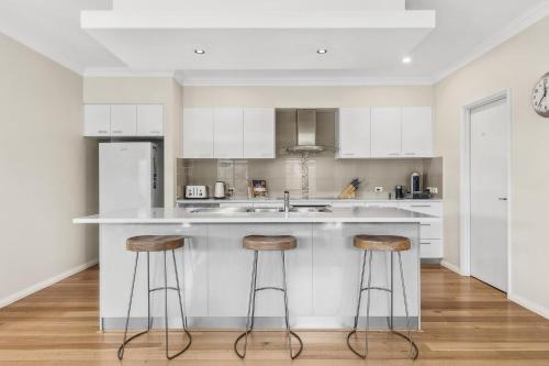 a kitchen with white cabinets and bar stools at The Dunsborough Drift Family Holiday Home in Dunsborough