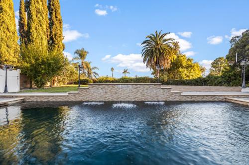 a pool of water in a park with palm trees at Villa Oasis: Unrivaled Views & Endless Space in Los Angeles