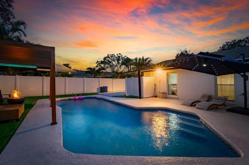 a swimming pool with an umbrella in a backyard at Sleeps 17! Beach & Heated Pool, 10 minutes to all Tampa attraction! in Tampa