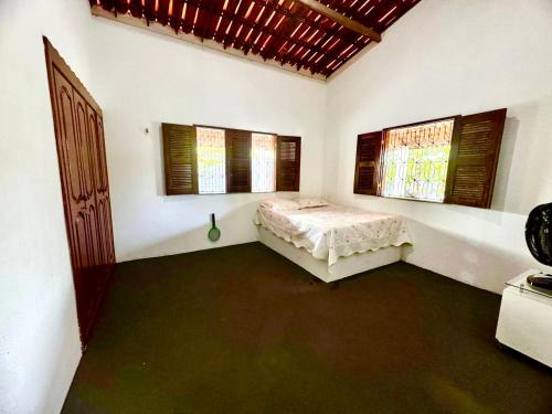 a bedroom with a bed in a room with windows at Toca do coelho in Aquiraz