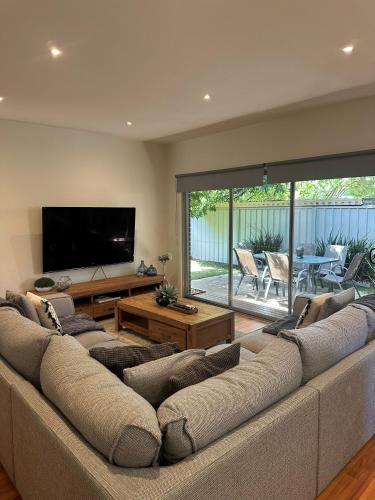 a living room with a large couch and a flat screen tv at L'barza Delightful Family Townhouse with courtyard - 3 bedrooms in Shepparton