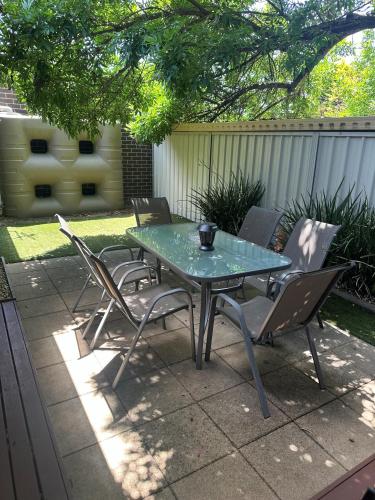 a glass table and chairs on a patio at L'barza Delightful Family Townhouse with courtyard - 3 bedrooms in Shepparton