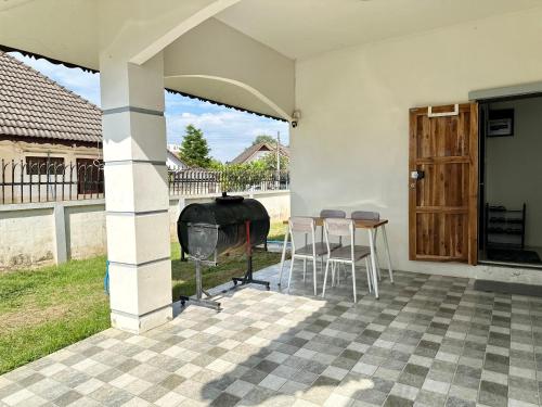 an outdoor patio with a grill and a table and chairs at Cozy 3 BR house & green lawn near Airport & Old town in Chiang Mai