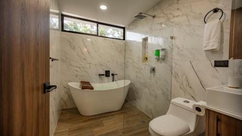 a bathroom with a tub and a toilet and a sink at Villa El Bosque Dorado in Fortuna