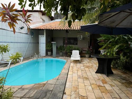a swimming pool with an umbrella next to a house at Casa Aconchegante Tamandaré in Tamandaré