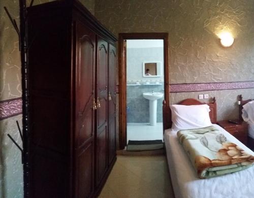 a bedroom with a bed and a bathroom with a sink at Hotel Espace Tifawine in Tafraoute