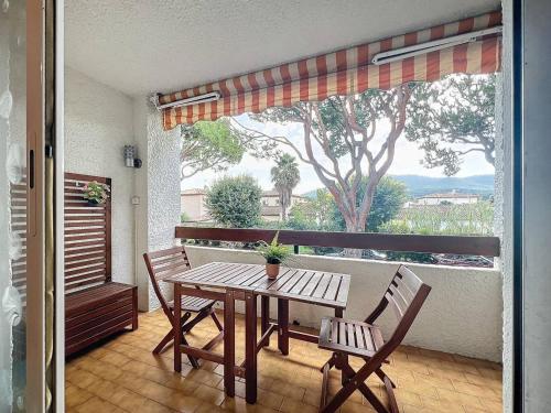 d'une table et de chaises en bois sur un balcon avec une fenêtre. dans l'établissement Appartement 2-4 pers, proche plage, parking privatif - FR-1-770-40, à Saint-Cyr-sur-Mer