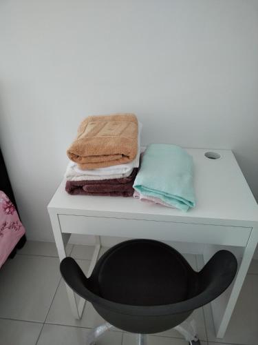 a white desk with a black chair and towels at Anderson Condo ipoh in Ipoh