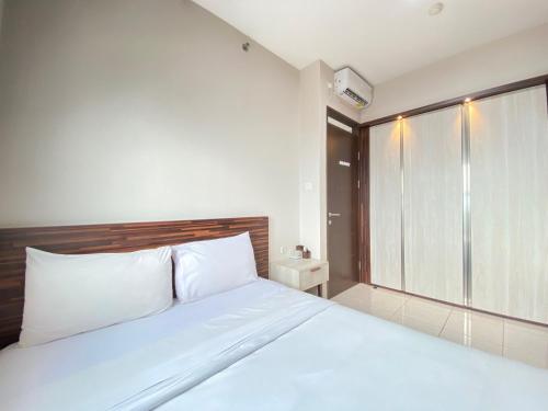 a bedroom with a large white bed and a window at Chic and Cozy 2BR at Mekarwangi Square Cibaduyut Apartment By Travelio in Bandung