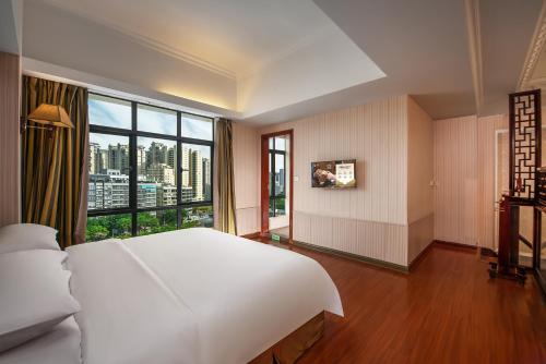 a bedroom with a large white bed and a large window at Vienna International Hotel Jieyang Jieyanglou in Jieyang