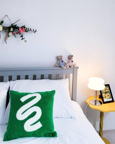 a bed with a green pillow with a s on it at Seoul 리베스폴 3room KSPO-DOM Family trip in Seoul