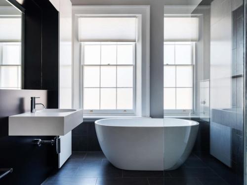 a bathroom with a large white tub and a sink at The Macquarie in Hobart