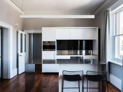 a kitchen with white cabinets and a black counter top at The Macquarie in Hobart