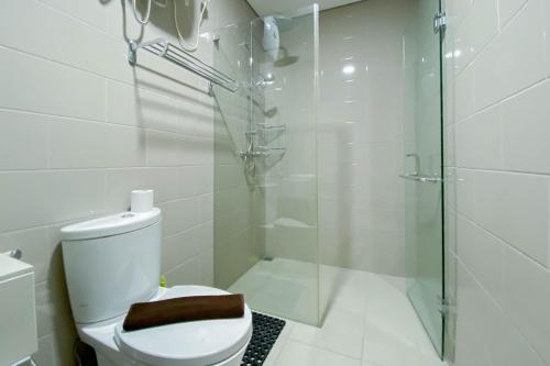 a bathroom with a toilet and a glass shower at Best Deal and Comfort 1BR at Citralake Suites Apartment By Travelio in Jakarta