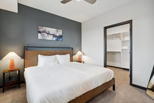 a bedroom with a large white bed and a mirror at CozySuites Mass w parking lounge & roof deck #26 in Indianapolis